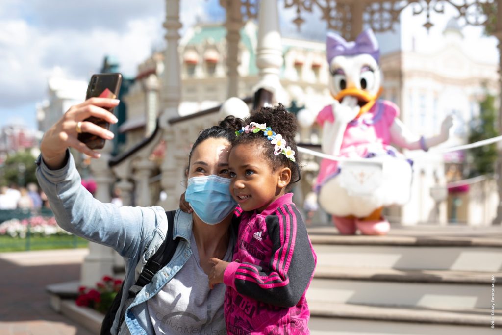 A mother and her daughter take a picture in front of the scene where Daisy is.