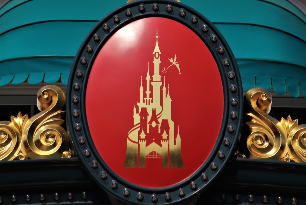 Le logo de disneyland or et rouge, en forme de château, avec la fée clochette