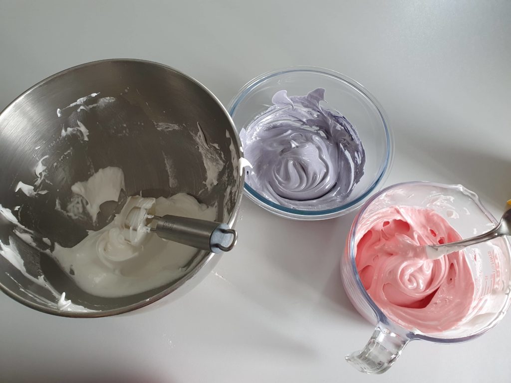 Trois récipients avec de la meringue de couleur différente.