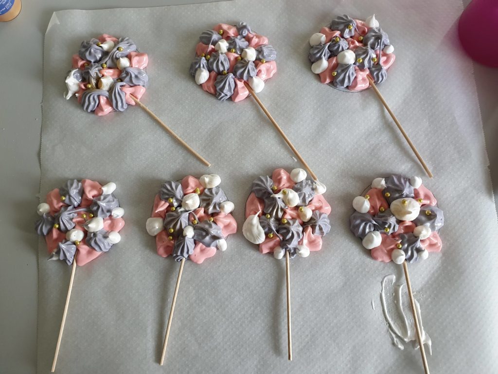 Food pearls and sticks are placed on the meringue to create lollipops