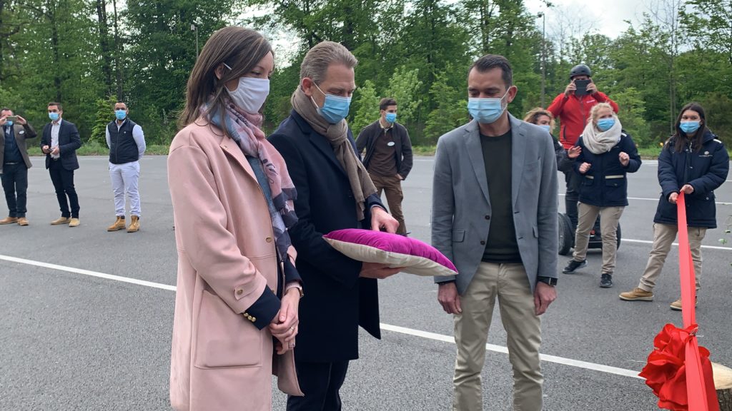 Le directeur tient le coussin avec les ciseaux pour couper le ruban rouge