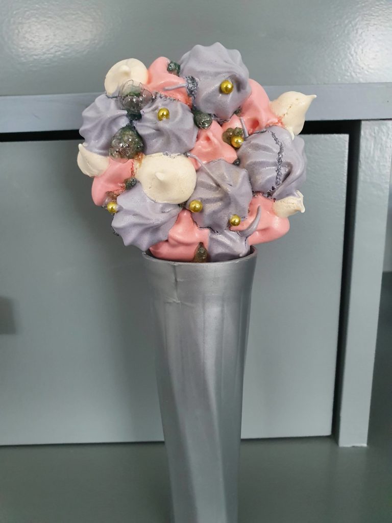 LE résultat final, une sucette-meringue Raiponce, présentée dans un pot torsadé et gris, à la manière d'une fleur