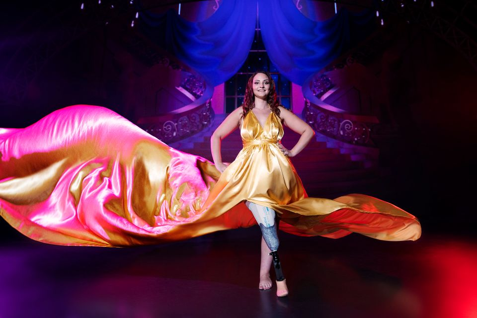 Une femme P.M.R (avec une jambe artificielle) vêtue de la robe de princesse aux couleurs de Belle. 