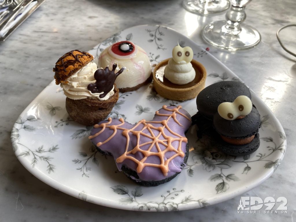 une assiette de friandise d'halloween avec une patisserie en forme d'oeuil, une tête de mickey décoré d'une toile d'araignée comestible